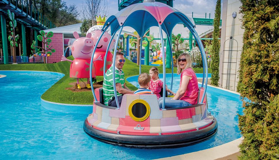 a mom, dad and their 2 children sat in a peppa pig boat ride